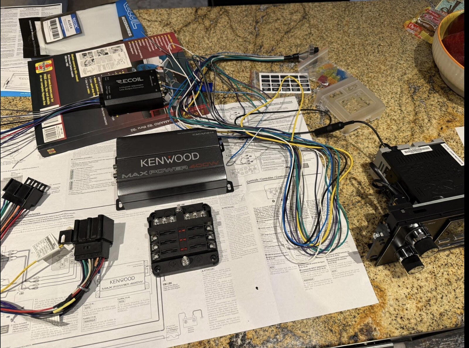 Kenwood amp, retro head unit, wiring, and Camaro Haynes manual spread on the counter — tap to enlarge